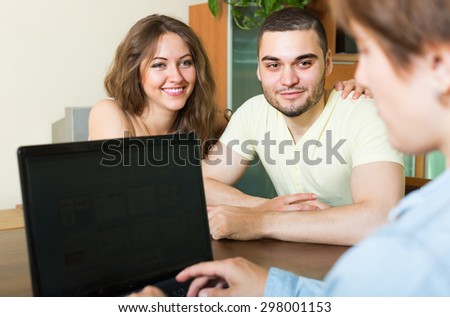 Young married couple talking with employee at the table and smiling