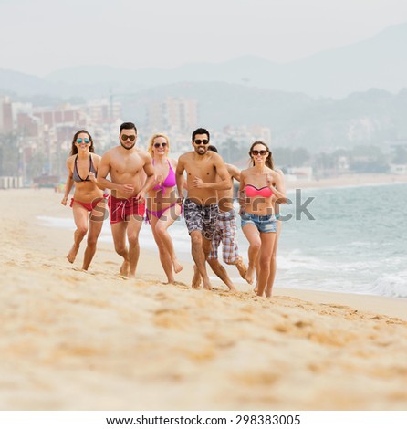 Group of people running at sea beach in summer day