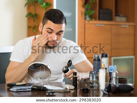 Young man putting cream for keeping his skin in good shape