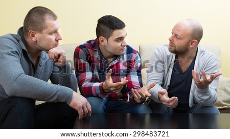 Serious adult male friends sitting at the table and sharing the problems
