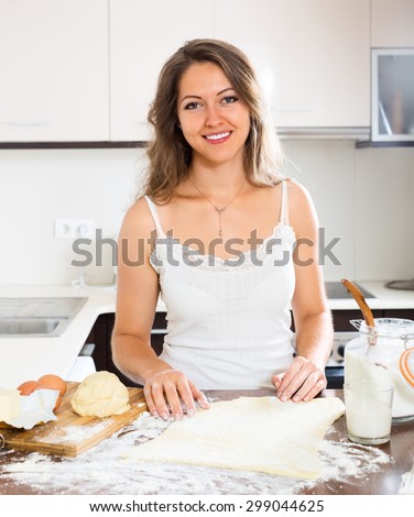 happy beautiful woman preparing cakes of dough at kitchen