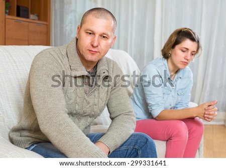 Family quarrel at home. Sadness man against unhappy young woman
