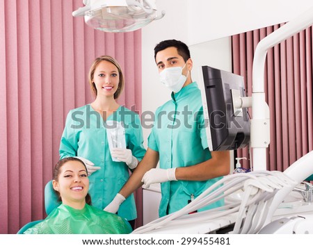 Serious dentist, assistant and happy patient at surgery office