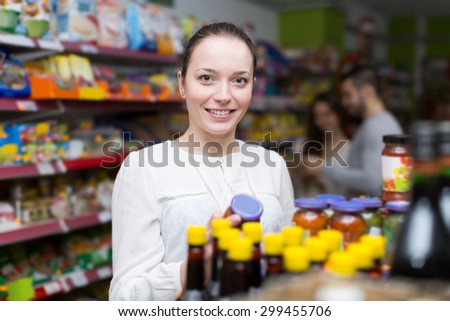 Positive russian customers standing near shelves with canned goods at shop