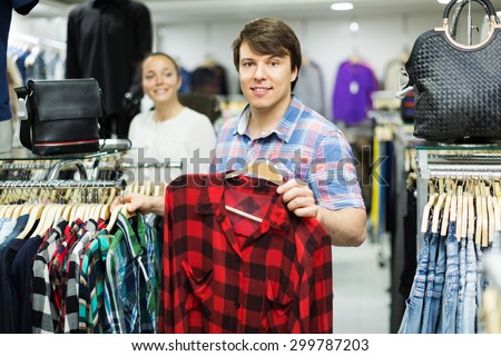 Happy couple choosing clothes in commercial centre