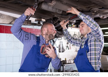 Two smiling american  people fixing car tire leak