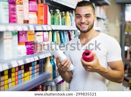 Attractive young man buying shampoo in shopping mall