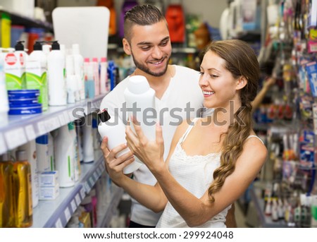 Adult woman in good spirits selecting shampoo at a store