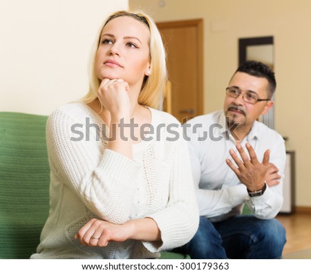 Family quarrel. Sad guy and angry woman during quarrel  in living room