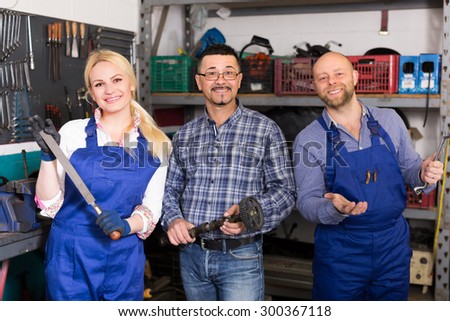 Portrait of auto service center crew with attractive young blonde near tools and equipment