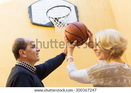 Positive senior spouses throwing the ball into basket