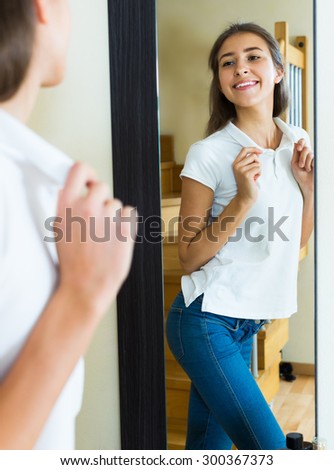 Happy young girl looking at her reflection in the mirror