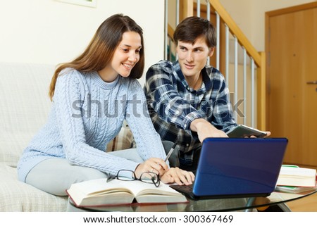 Happy young  students doing homework with laptop at home
