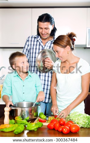 Happy family of three cooking vegetables together in home kitchen