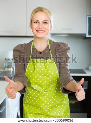 Cheerful smiling female turned up the thumbs in kitchen