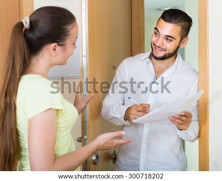 Smiling american man and woman standing with papers at the door