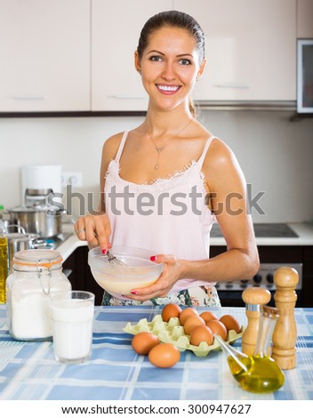 Happy girl cooking omelette with milk for breakfast