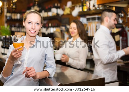 Positive american female drinking wine at counter
