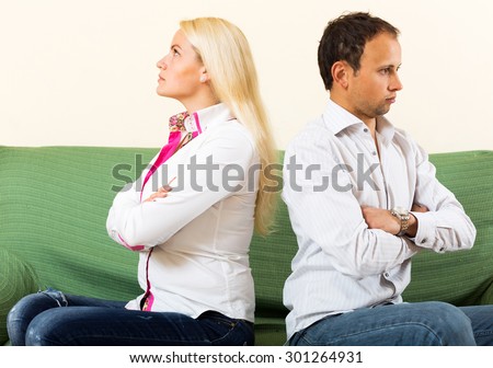Family quarrel. Sad guy and young woman during quarrel  in living room at home
