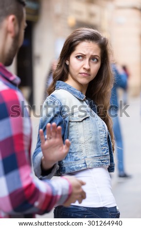 Beautiful woman getting rid of an annoying man who is trying to pick her up on a street