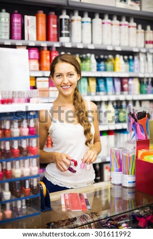 Smiling store clerk with nail polish at cash desk