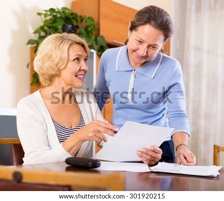 Happy mature ladies signing documents at home.Focus on the woman on the left