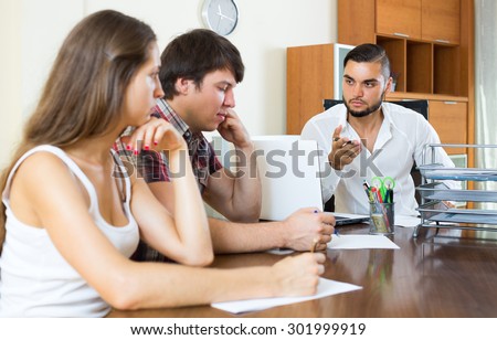 Bank employee in the office trying hard to make couple pay back a loan