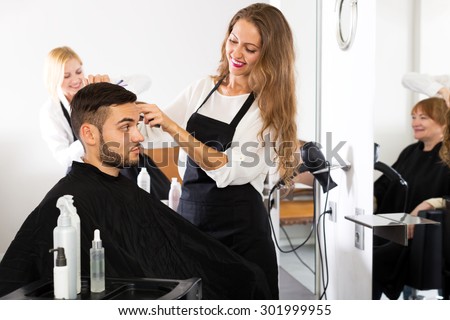 guy cuts hair and female barber at the hair salon. Focus on the man