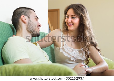 Happy smiling young adult couple in the living room at home