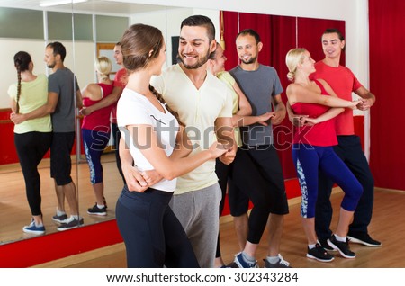 Group of smiling russian people dancing salsa in studio