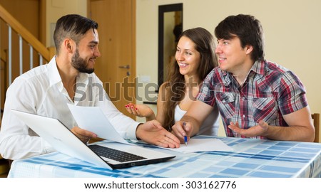 Young happy salesman try hard to sign a business contract with merried couple