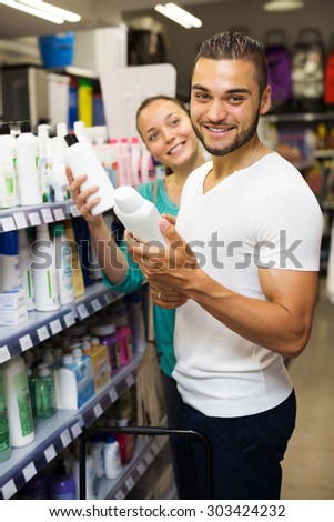 Young man chooses shampoo in shopping mall