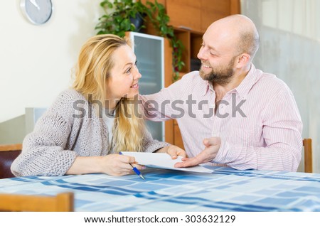 Positive smiling couple discussing details of marriage settlement at home