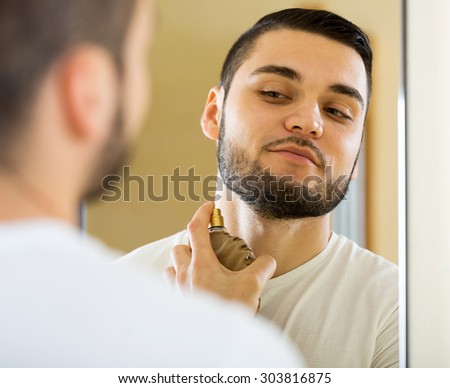 portrait smiling man applying perfume for keeping fresh