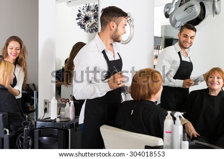 Barber cuts hair Mature woman at the hair salon