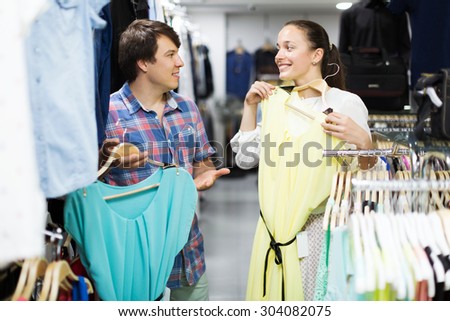 Merry couple choosing clothes in the shop