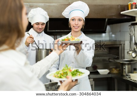 Team of happy chefs and young waiter at the restaurant kitchen