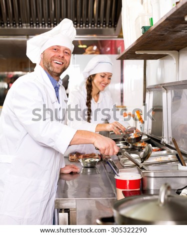 Positive  professional chefs working in restaurant kitchen