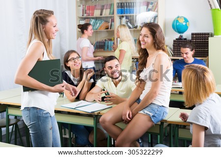 Several happy students having a conversation sitting in the classroom