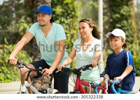 family of three cycling across city in summer day