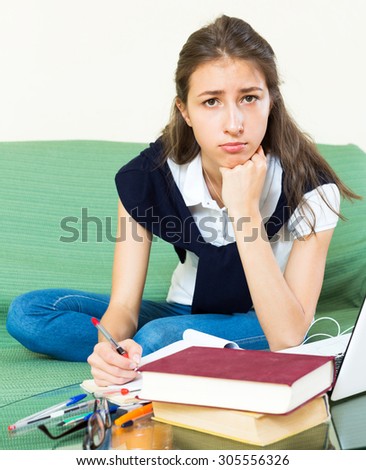 Unhappy girl college student study sitting on a sofa in the living room