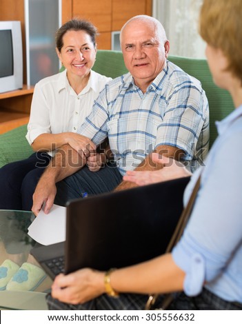 Aged couple answer questions of social worker with laptop at home and smiling. Focus on man