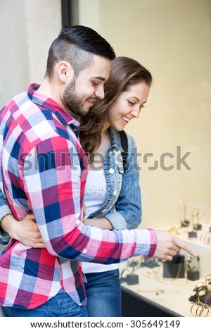 Young couple standing close to each other and choosing expensive watch for a present