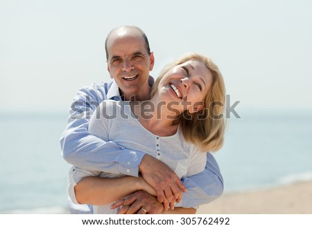 Portrait of mature woman with elderly man against sea in background