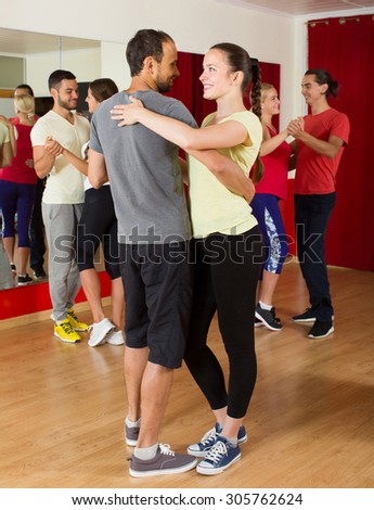 Group of positive spanish people dancing salsa in studio