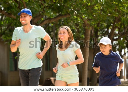 Sports parents with son jogging outdoors summer day