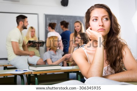 Bored lonely female student sitting in classroom at her desk