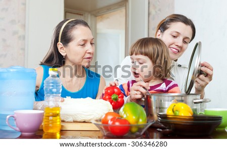 women with baby girl cook with vegetables and oil in kitchen at home