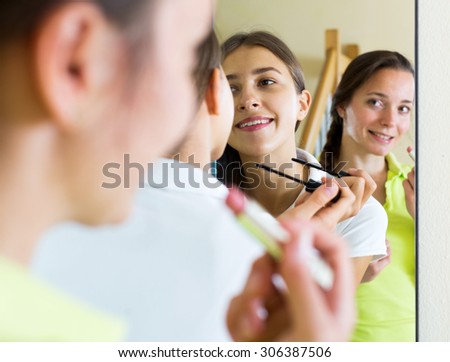 Adult beautiful woman making make-up near mirror. Focus on the left woman