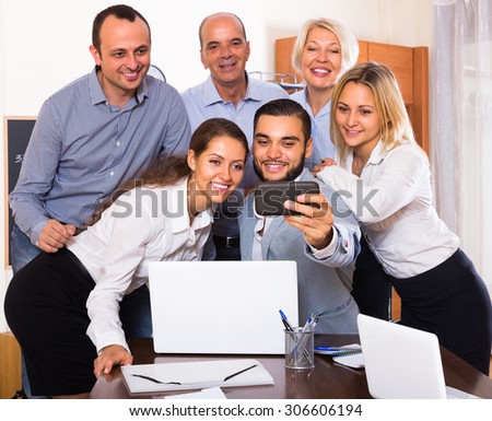 Smiling employees doing selfie using smartphone at office